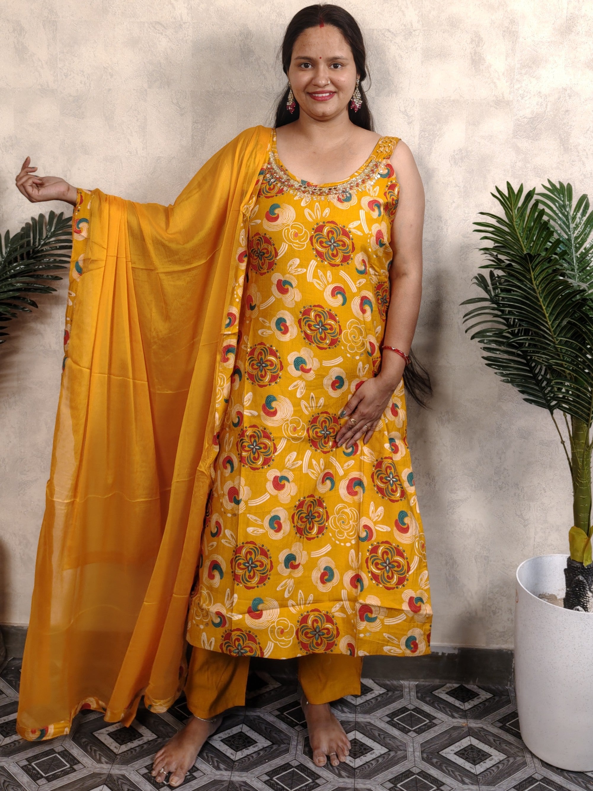 Woman wearing a yellow traditional outfit with a patterned dress and saree, standing indoors.